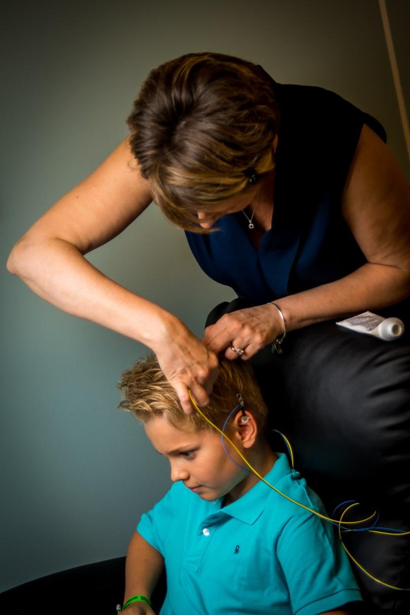 A trainer gently places sensors for a boy before his session
